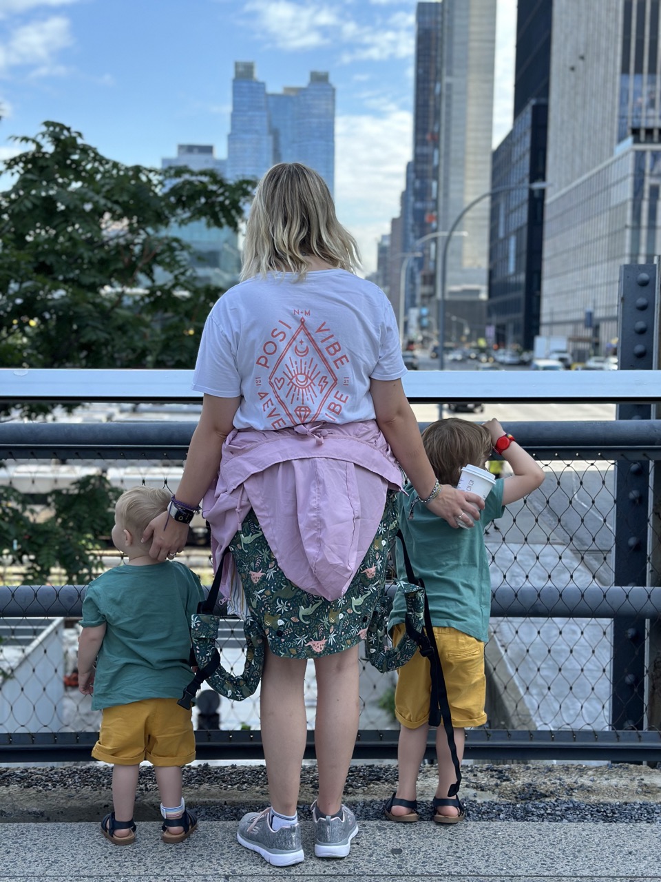 Mum and two kids - a toddler and preschooler both dressed in a green tshirt and yellow shorts, look out on New York